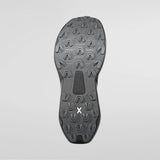 The outsole of a black athletic shoe, showing deep tread patterns and a small white stylized 'X' logo near the heel, photographed against a light gray background. - La Sportiva Prodigio 2 GORE-TEX Shoes (Men's) - Black/Reflective