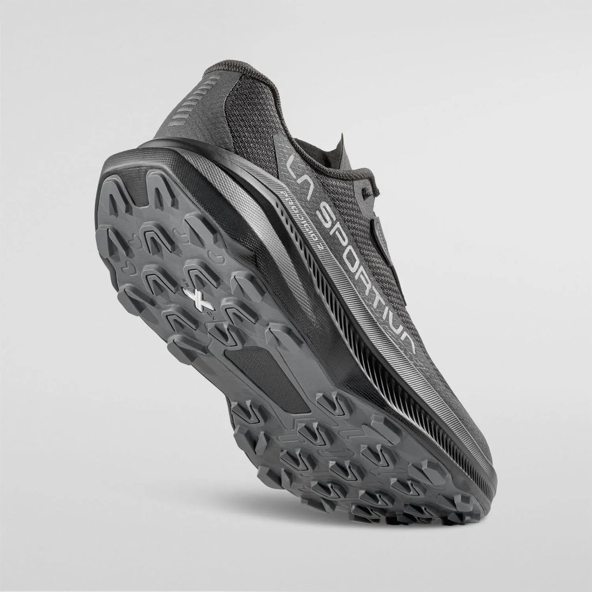 A dark gray and black trail running shoe shown from a three-quarters angle, highlighting its rugged treaded outsole and side branding, set against a light gray studio background. - La Sportiva Prodigio 2 GORE-TEX Shoes (Men's) - Black/Reflective