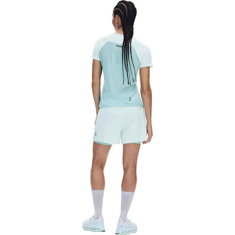 A woman shown from the back wearing a light blue and white athletic t-shirt and matching white shorts, with white socks and white sneakers, against a plain white background. - On Performance-T (Women's) - Flurry/Aquamarine