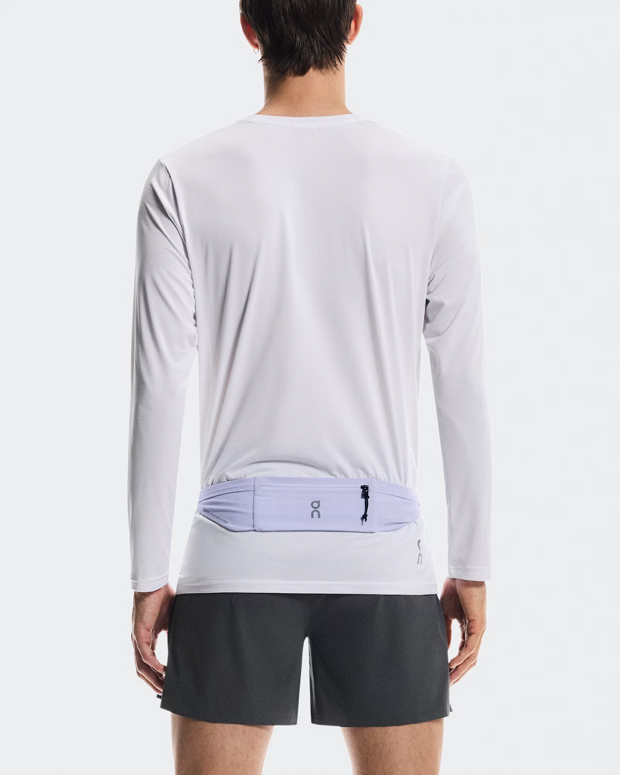 Person wearing a white long-sleeve shirt and black shorts with a visible brand logo on a white background - On Speed Belt (Unisex) - Thistle