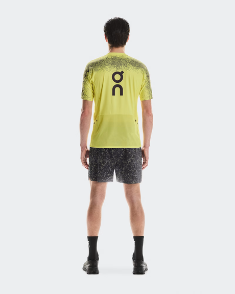 Person wearing a bright yellow sports shirt and black shorts with a brand logo on a white background - On Ultra Shorts (Men's) - Iron/Lime