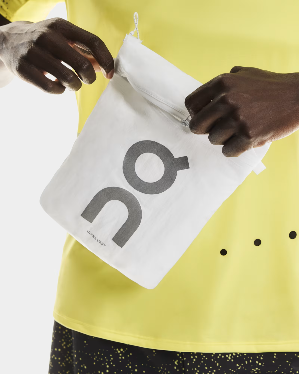 Person holding a white bag with 'on' logo against a yellow background - On Ultra Vest Pro (Unisex) - White
