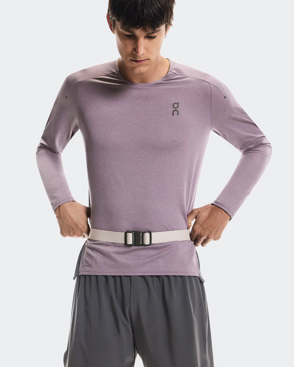 Person wearing a light purple long-sleeve athletic shirt and gray shorts on a white background - On Speed Belt (Unisex) - Fog