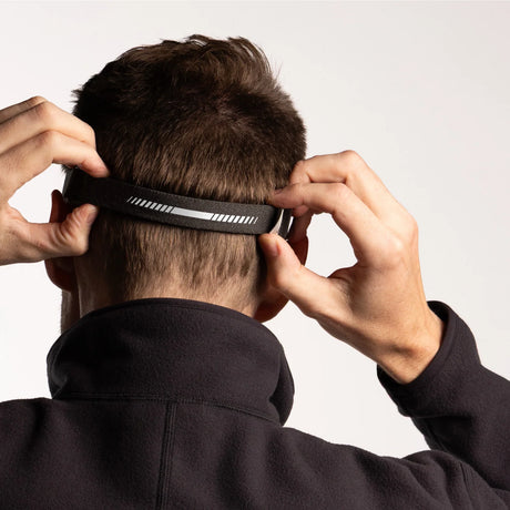Person adjusting a black headband on a plain background - Biolite Range 500 Headlamp - Midnight Grey