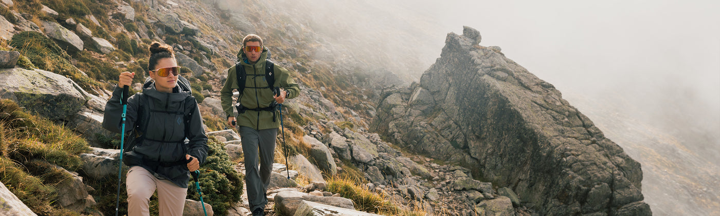 Two hikers on a rocky mountain trail in black diamond equipment and apparel with foggy background