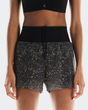 Black athletic shorts with gold star pattern worn by a person on a white background - On Ultra Shorts (Women's) - Iron/Lime