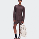 A male model stands against a light gray studio background wearing a matching brown athletic long-sleeve shirt and shorts set, black socks, and trail running shoes, while holding a cream-colored backpack. - On Trail Long-T Solar (Men's) - Mulberry