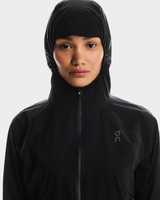 Person wearing a black hooded jacket with a brand logo on a white background - On Performance Jacket (Women's) - Black