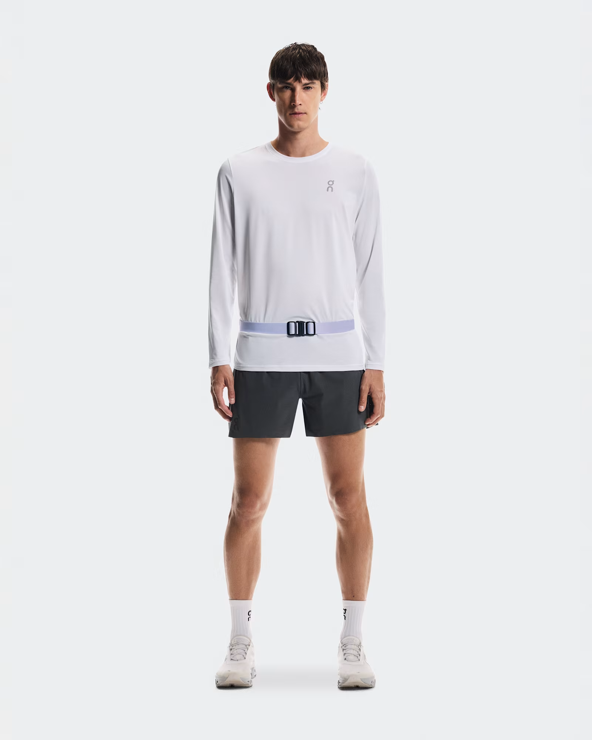 Person wearing a white long-sleeve shirt and black shorts with a visible brand logo on a white background - On Speed Belt (Unisex) - Thistle