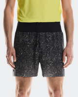 Person wearing black shorts with white speckle pattern and a yellow top on a light gray background - On Ultra Shorts (Men's) - Iron/Lime