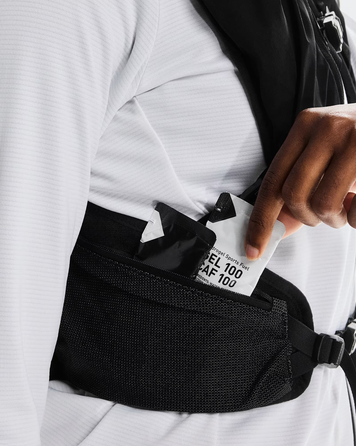 Person wearing a black waist bag with a white label, holding a card. - On Trail Pack 20L - Black