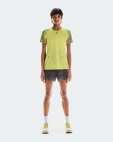 Person wearing a bright yellow athletic shirt and black patterned shorts on a white background - On Ultra Shorts (Women's) - Iron/Lime