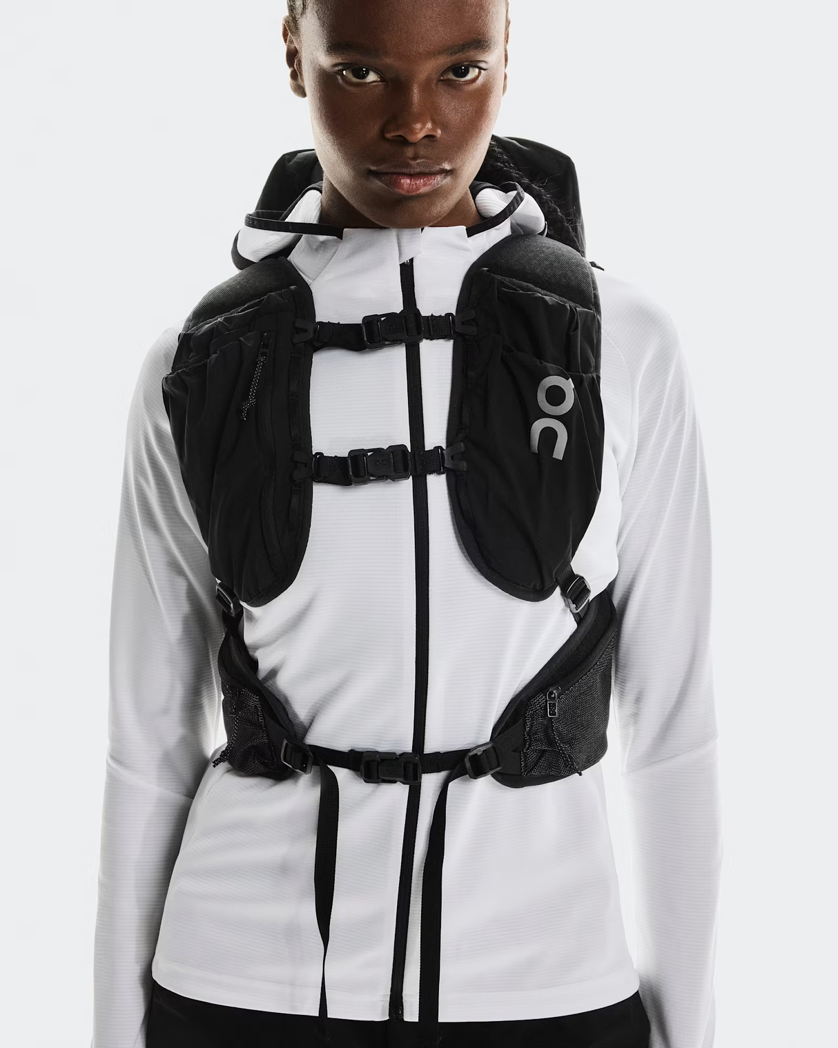 Person wearing a white jacket with a black backpack on a light gray background - On Trail Pack 20L - Black