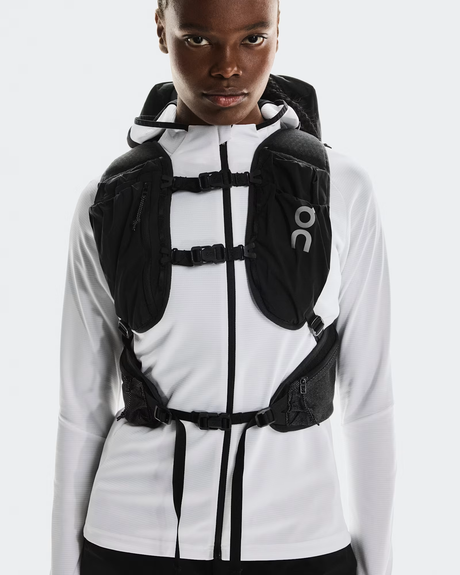Person wearing a white jacket with a black backpack on a light gray background - On Trail Pack 20L - Black