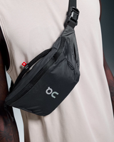 Black waist bag with a visible brand logo worn by a person against a neutral background - On Waist Pack 2L Lite - Magnet