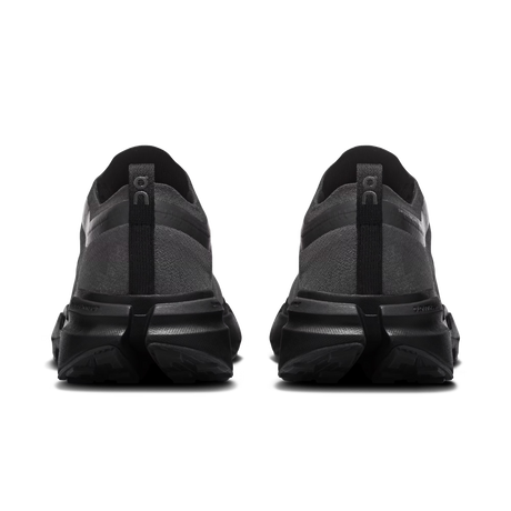 A pair of black and dark gray athletic sneakers shown from the rear, featuring chunky black midsoles and heel pull tabs with the 'On' logo, on a plain white background. - On Cloudsoma Shoes (Women's) - Black/black