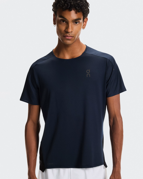 Man wearing a navy blue t-shirt with a brand logo on a white background - On Performance-T (Men's) - Navy/Black