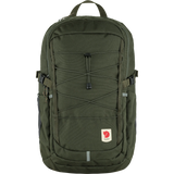 A Fjällev backpack in olive green, featuring a front zippered pocket with crisscross compression straps, side pockets, and the signature Fjällev logo patch on the lower front, set against a plain white background. - Fjällräven Skule 28 Backpack - Deep Forest