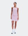 A woman modeling a light pink athletic set consisting of a sleeveless tank top and matching shorts, paired with white socks and white sneakers, against a solid light gray background. - On Performance Tank (Women's) - Foxglove/Orchid