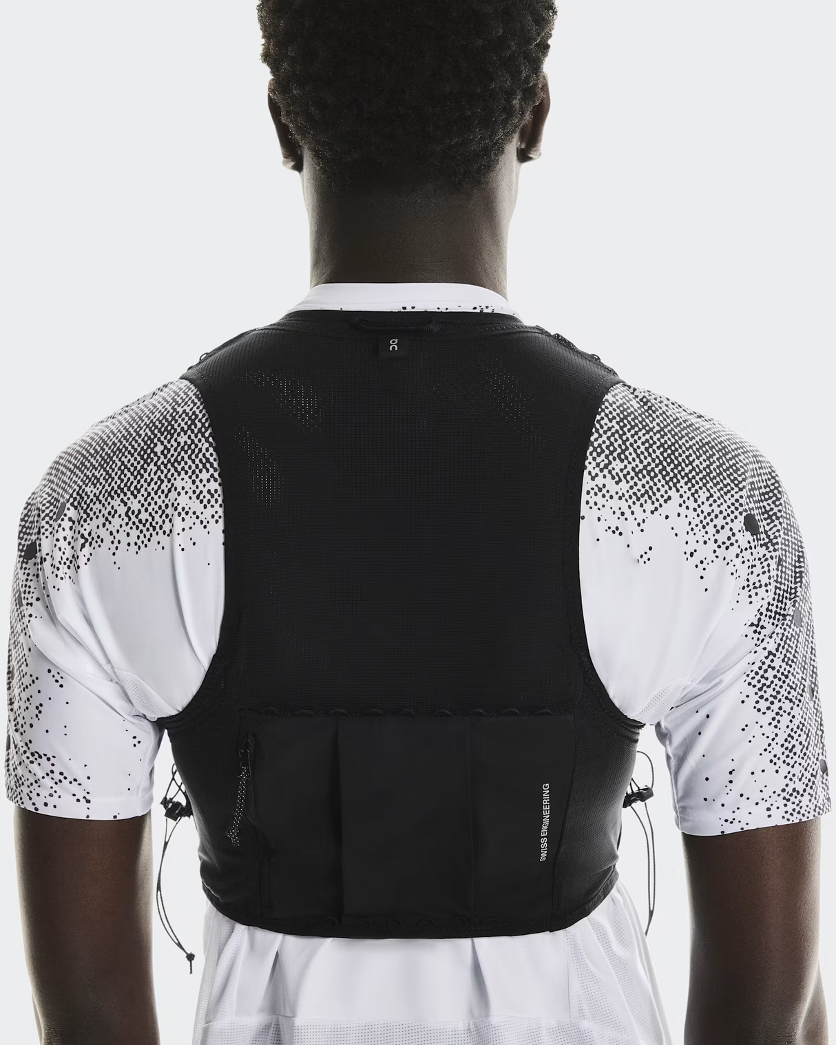 Person wearing a black athletic vest over a white shirt with black patterns on a light gray background - On Ultra Vest Pro (Unisex) - Black