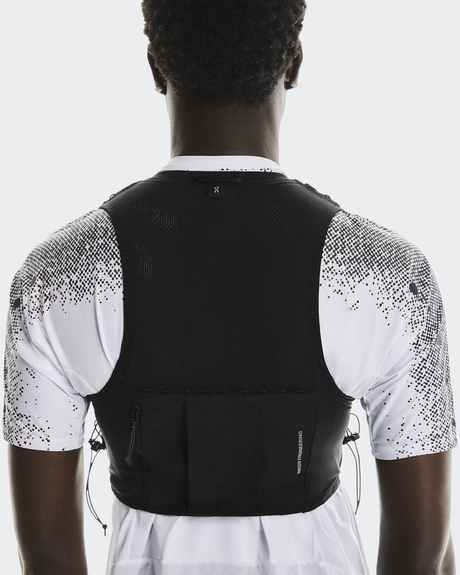 Person wearing a black athletic vest over a white shirt with black patterns on a light gray background - On Ultra Vest Pro (Unisex) - Black