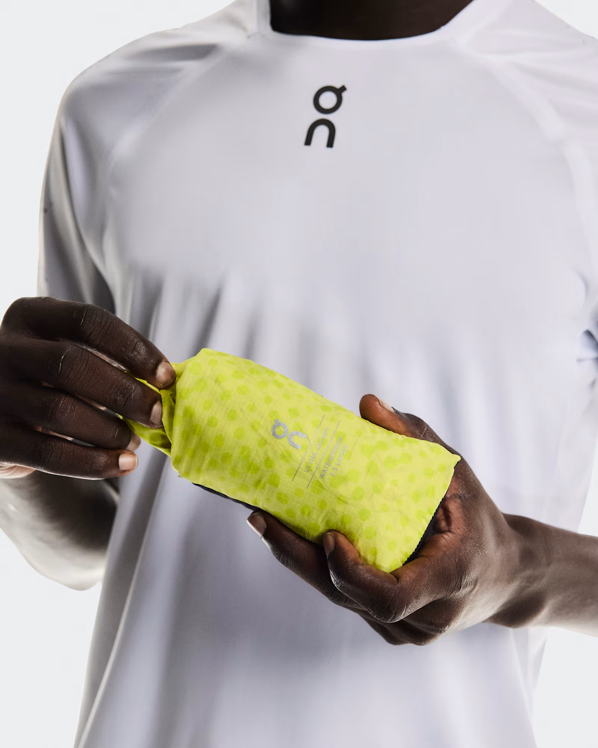 Person holding a yellow towel with a brand logo on a white background - On Ultra Jacket (Men's) - Limelight/Lime