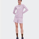 A woman modeling a light pink athletic long-sleeve top and matching shorts against a plain light gray studio background. - On Trail Shorts (Women's) - Foxglove