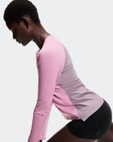Person wearing a pink and gray athletic outfit on a white background - On Performance Long-T (Women's) - Dewberry/Sakura