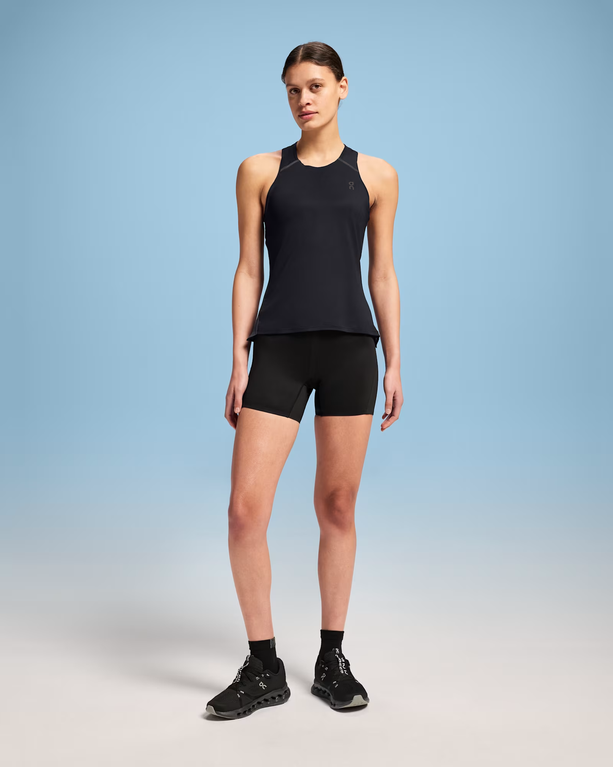 Person wearing a black tank top and shorts on a gradient background - On Performance Tank (Women's) - Black/Eclipse