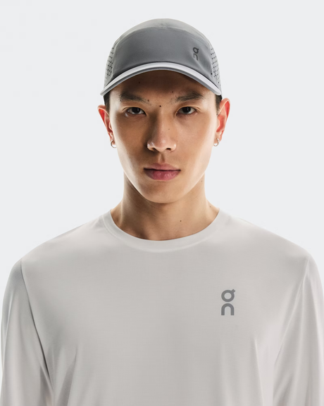 Person wearing a gray cap and white shirt with a brand logo on a white background - On Lightweight Cap - Rock