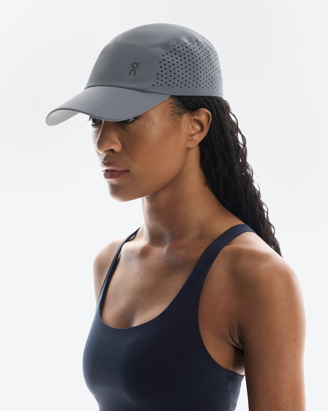 Woman wearing a gray cap with a brand logo on a white background - On Lightweight Cap - Rock
