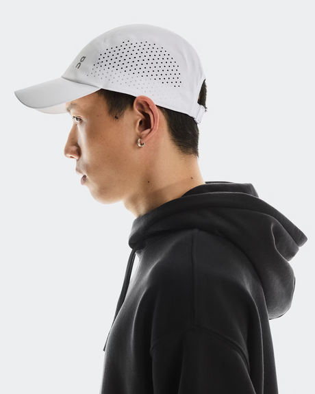 Person wearing a white cap and black hoodie on a light gray background - On Lightweight Cap - White