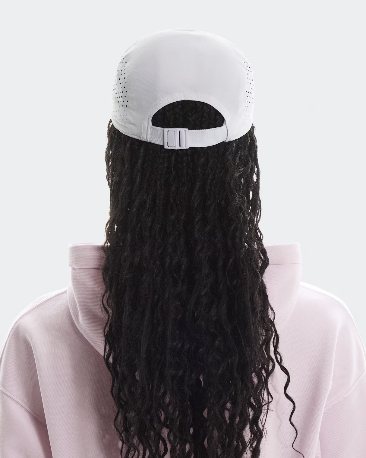 Person wearing a white cap with a long black wig attached on a light gray background - On Lightweight Cap - White
